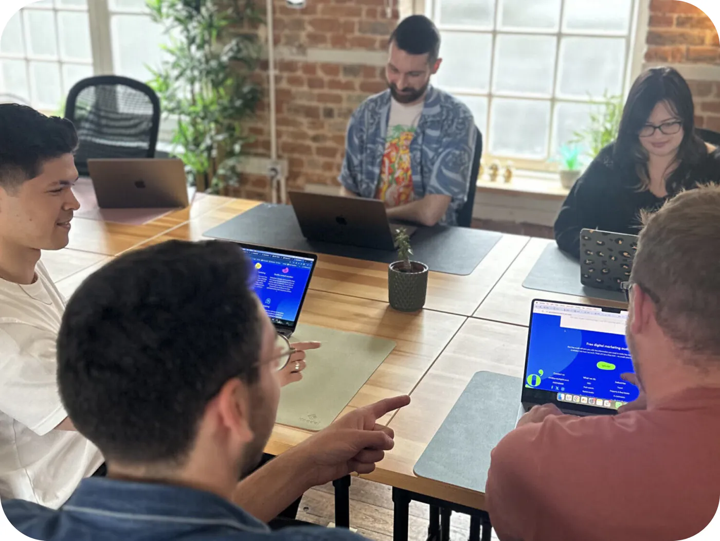 The Gooey Digital team reviewing work together at a laptop-covered desk